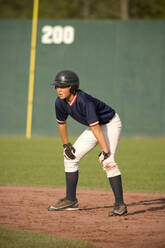 Junger Baseballspieler auf dem Weg zur Base mit den Händen auf den Knien - CAVF86232