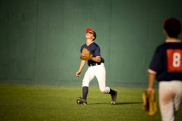 Junger Baseballspieler mit Sonnenbrille, der zu einem Flugball aufschaut - CAVF86235