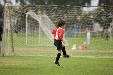 Young boy skipping in front of goal on a soccer field - CAVF86248