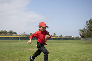 Kleiner Junge hält seinen Handschuh und läuft über das Tballfeld - CAVF86266