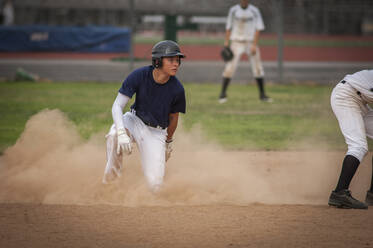 Junger Baseballspieler in einer Staubwolke, nachdem er in die zweite Base gerutscht ist - CAVF86277