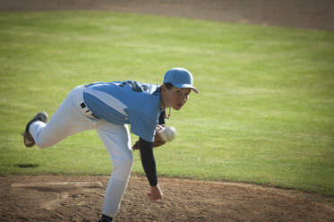 Pitcher in hellblau-weißem Trikot beim Aufziehen auf einem Baseballfeld. - CAVF86281