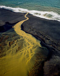 Luftaufnahme eines verzweigten orangefarbenen Flusses, der im Süden in den Ozean fließt - CAVF86282