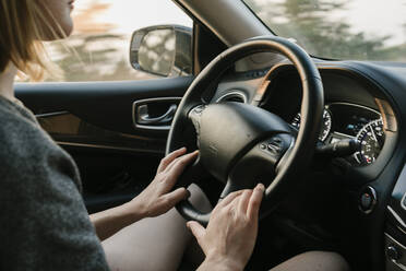 Innenansicht einer Autofahrerin in Big Sur bei Sonnenuntergang - CAVF86307