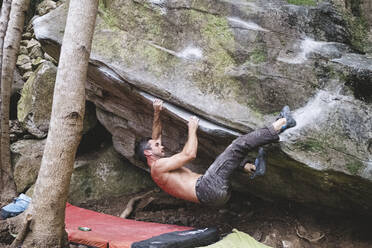 Ein männlicher Kletterer klettert im Freien auf einen Felsen - CAVF86347