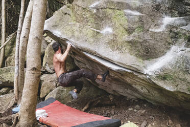 Ein männlicher Kletterer klettert im Freien auf einen Felsen - CAVF86349