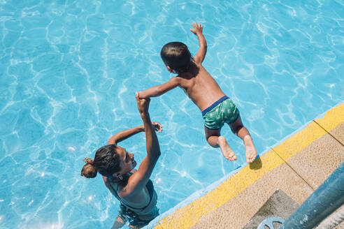 Eine Frau hilft einem Kind, in einen Pool zu springen - CAVF86366