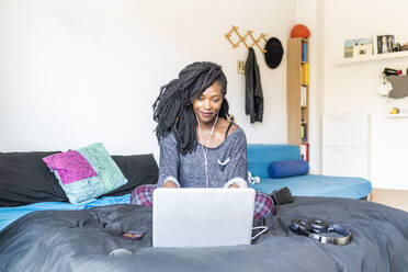Young woman using laptop on bed at home - MEUF01053