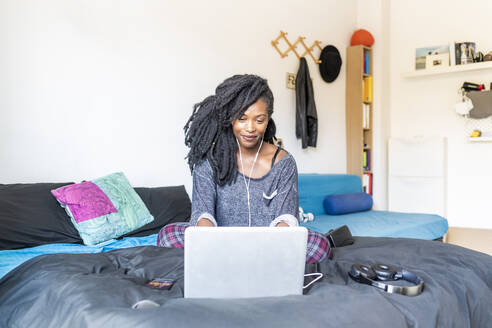 Junge Frau mit Laptop auf dem Bett zu Hause - MEUF01053