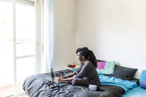Junge Frau mit Laptop auf dem Bett zu Hause - MEUF01054