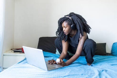 Young woman using laptop on bed at home - MEUF01072