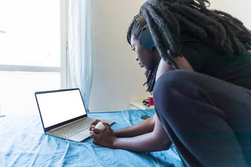 Young woman using laptop on bed at home - MEUF01073