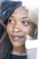 Portrait of young woman with dreadlocks looking out of the window - MEUF01078