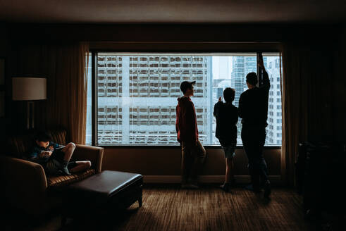 Ein Mann und ein Junge schauen aus dem Fenster auf die hohen Gebäude der Stadt draußen. - CAVF86406