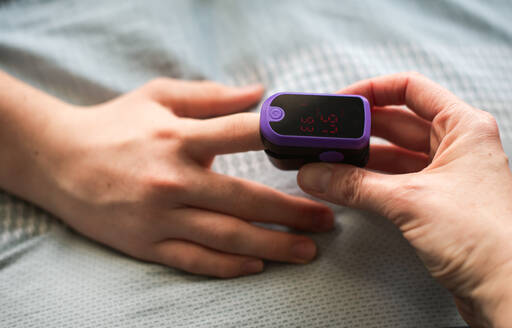 Close up of a hand putting a pulse oximeter on someone's finger. - CAVF86415