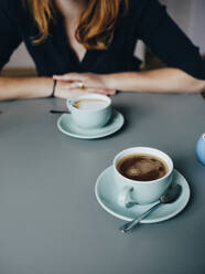 Eine Frau und zwei Tassen Kaffee im Cafe - CAVF86479