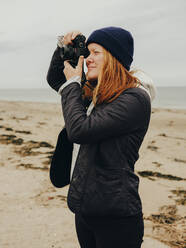 Frau macht Fotos am Strand in Schottland - CAVF86487