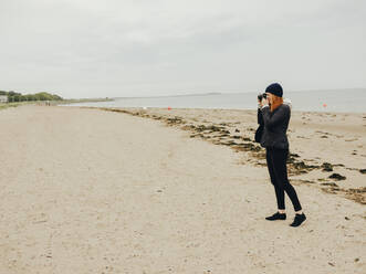 Frau macht Fotos am Strand in Schottland - CAVF86489