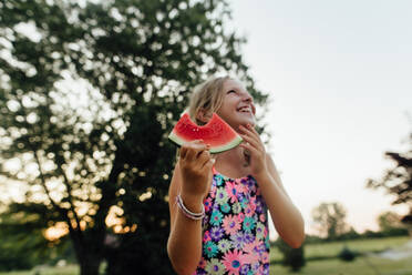 Junges Mädchen mit großem Lächeln isst Wassermelone im Sommer draußen - CAVF86496