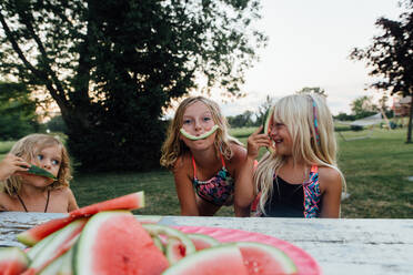 Kleine Kinder albern herum, während sie im Sommer draußen Wassermelone essen - CAVF86501