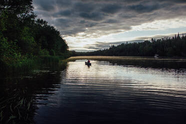 Mann paddelt in der Morgendämmerung flussabwärts in Nordkanada - CAVF86515