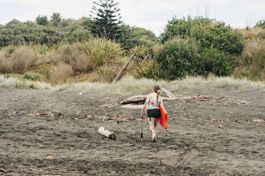 Junges Mädchen läuft auf schwarzem Sand am Strand - CAVF86526
