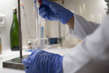 Close up of lab technician by placing a sample on beaker. - CAVF86539