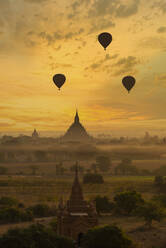 Myanmar, Region Mandalay, Bagan, Silhouetten von Heißluftballons, die in der nebligen Morgendämmerung über alten Tempeln fliegen - TOVF00199