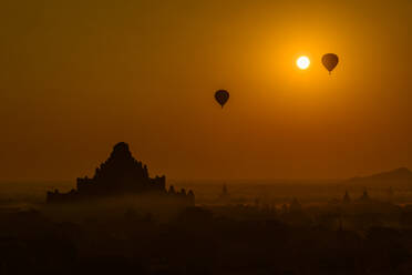 Myanmar, Region Mandalay, Bagan, Silhouetten von Heißluftballons, die in der nebligen Morgendämmerung über alten Tempeln fliegen - TOVF00204