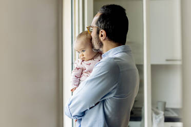 Father with baby looking out of the window at home - SODF00795