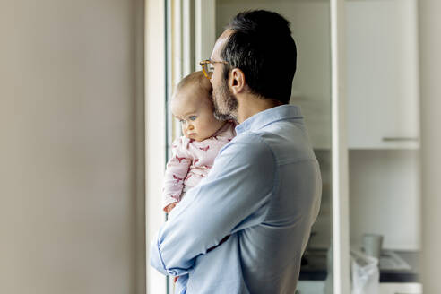 Vater mit Baby schaut zu Hause aus dem Fenster - SODF00795