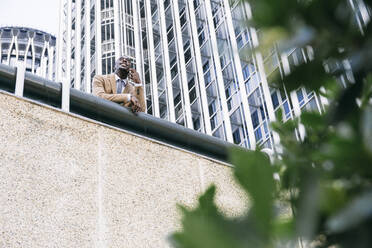 Young businessman leaning on a railing in the city talking on the phone - ABZF03230