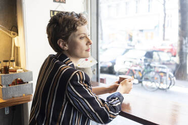 Pensive freelancer in a coffee shop looking out of window - TAMF02435