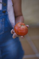 Mädchen mit geernteter roter Tomate in der Hand - LJF01624