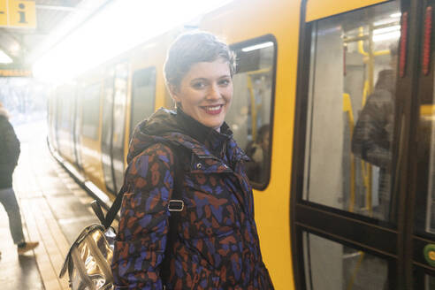 Porträt einer lächelnden Frau auf dem Bahnsteig, Berlin, Deutschland - TAMF02477