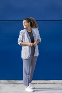 Smiling businesswoman in front of blue wall - SNF00442