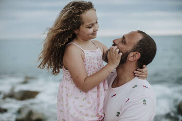 Tochter lächelt, während sie den Vater am Ufer betrachtet - GMLF00324