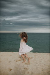 Carefree girl dancing on sand against sea - GMLF00333