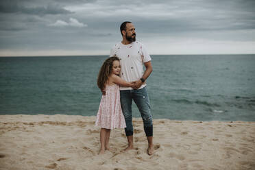 Daughter embracing father at beach - GMLF00336