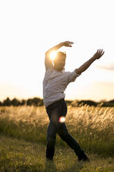 Man dancing at field in the evening light - MAUF03456