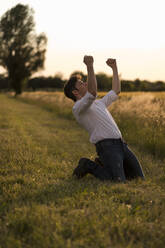 Man dancing at field in the evening light - MAUF03457