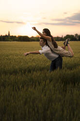 Dancing couple on field during sunset - MAUF03466