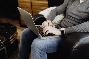 Man sitting at home, using laptop, close-up - DGOF01087