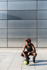 Young man with headphones and basketball at a metallic shining wall - JMPF00017