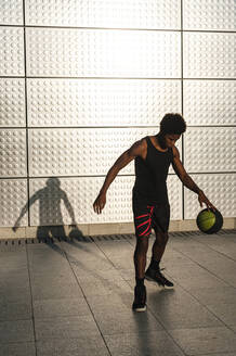 Young man playing basketball at a metallic shining wall - JMPF00024