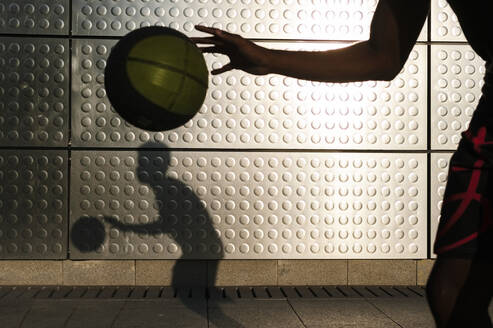 Young man playing basketball at a metallic shining wall - JMPF00027