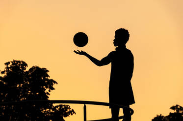 Silhouette eines jungen Mannes mit Basketball bei Sonnenuntergang - JMPF00045