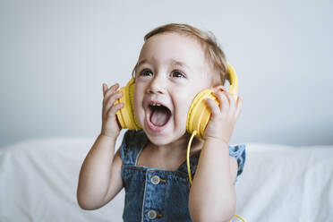 Kleines Mädchen zu Hause beim Musikhören im Bett - EBBF00325