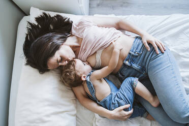 Mother breast feeding baby girl on bed - EBBF00345