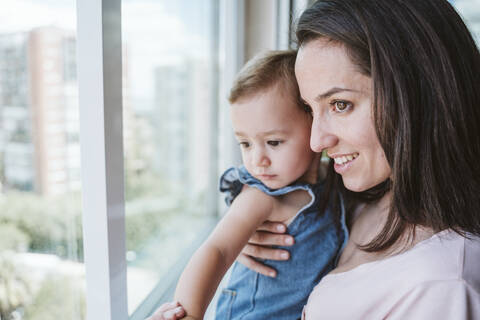 Mutter mit kleinem Mädchen zu Hause am Fenster, lizenzfreies Stockfoto